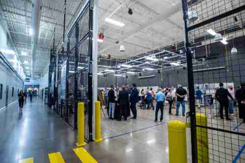 People walk around a big open room with concrete floors and a high-tech look.